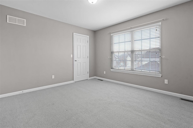 carpeted spare room with visible vents and baseboards