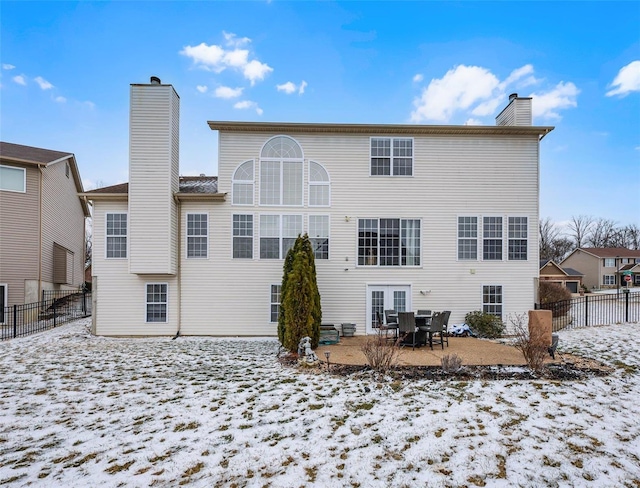 snow covered property featuring a chimney, a patio area, and fence