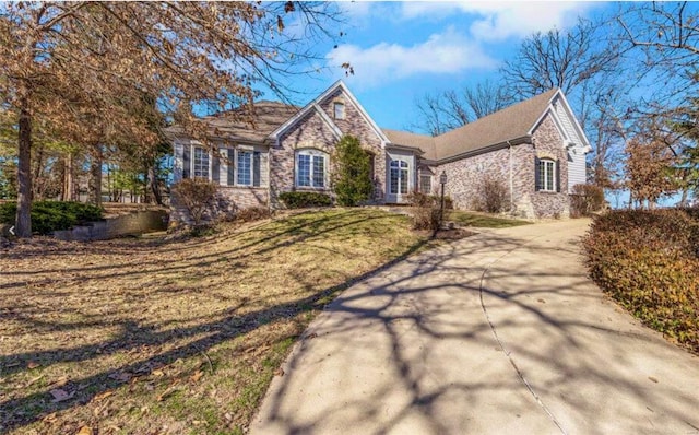 view of front of house with stone siding, a front lawn, and concrete driveway