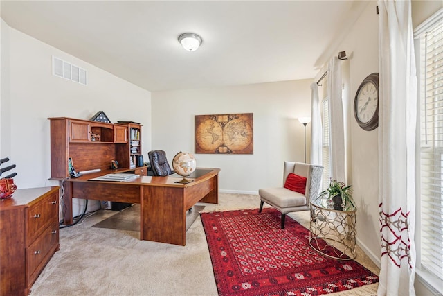 home office featuring light carpet, a healthy amount of sunlight, baseboards, and visible vents