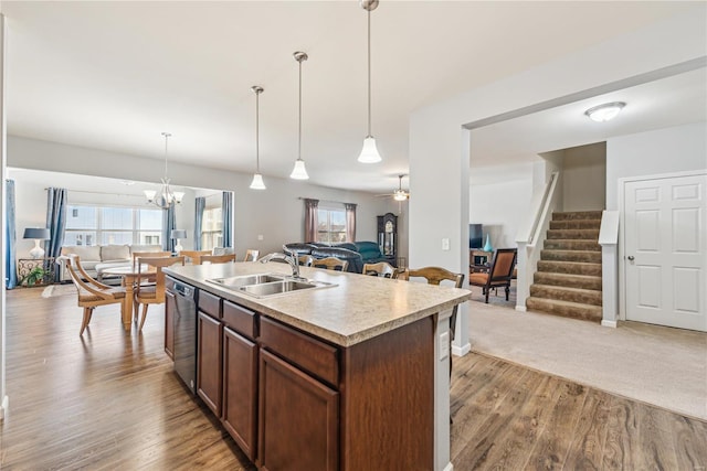 kitchen featuring open floor plan, light countertops, a sink, and stainless steel dishwasher