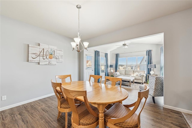 dining space with baseboards, vaulted ceiling, wood finished floors, and ceiling fan with notable chandelier