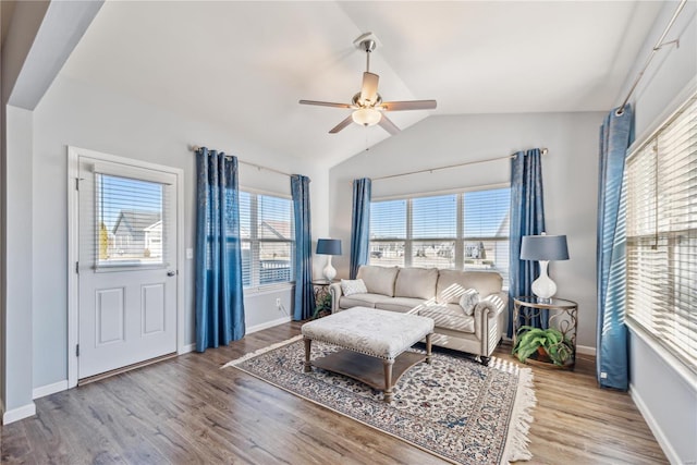 living room featuring ceiling fan, baseboards, vaulted ceiling, and wood finished floors