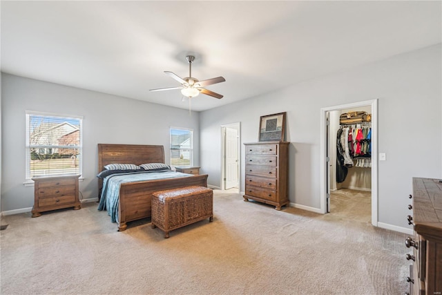 bedroom with a spacious closet, carpet flooring, a ceiling fan, and baseboards