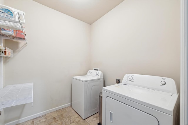 clothes washing area featuring laundry area, baseboards, and washing machine and clothes dryer