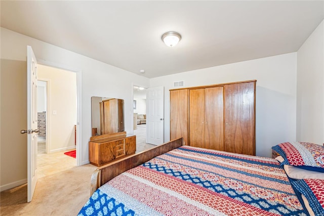 bedroom featuring baseboards, a closet, visible vents, and light colored carpet