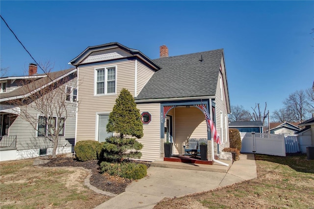 view of front of property with a shingled roof, a chimney, fence, and central AC