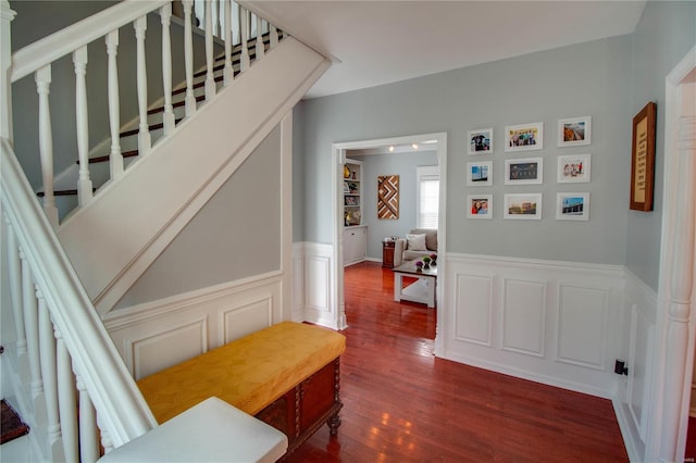 interior space featuring stairs, wainscoting, a decorative wall, and wood finished floors