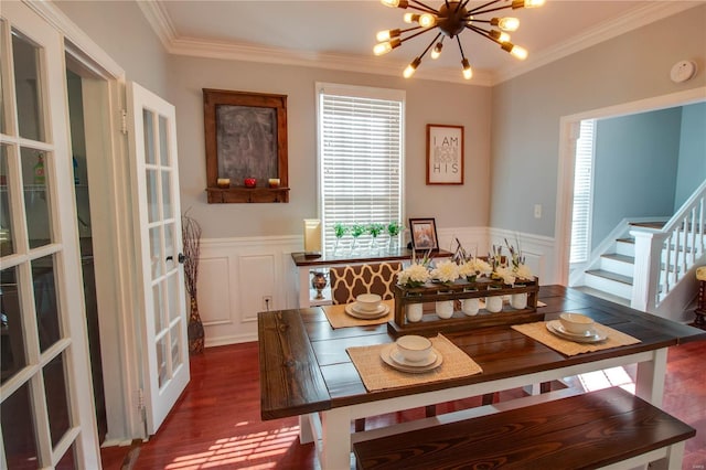 dining area with crown molding, wood finished floors, a notable chandelier, and wainscoting