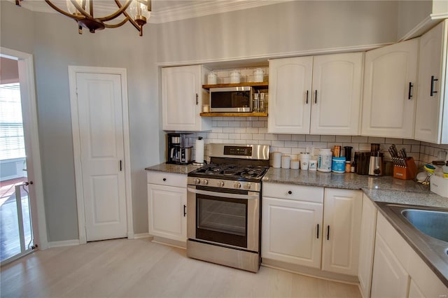 kitchen with stainless steel appliances, light wood-type flooring, white cabinetry, and decorative backsplash