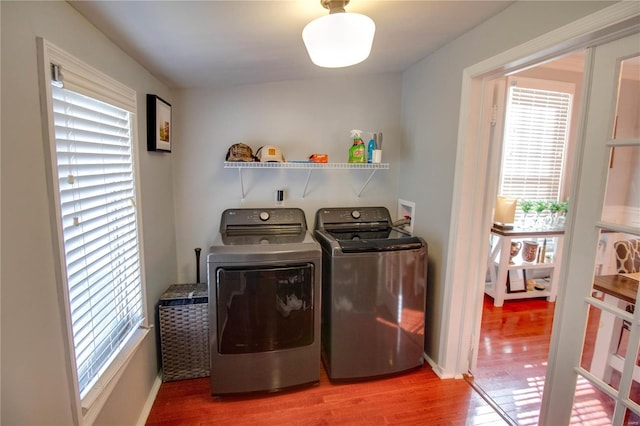 clothes washing area featuring laundry area, washer and clothes dryer, baseboards, and wood finished floors