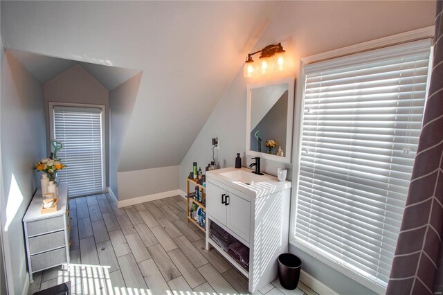 interior space with lofted ceiling, a sink, baseboards, and wood tiled floor