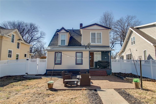 view of front facade featuring a shingled roof, a chimney, a fenced backyard, and a gate