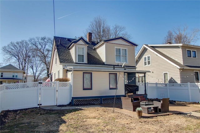 back of house with a shingled roof, a gate, and fence