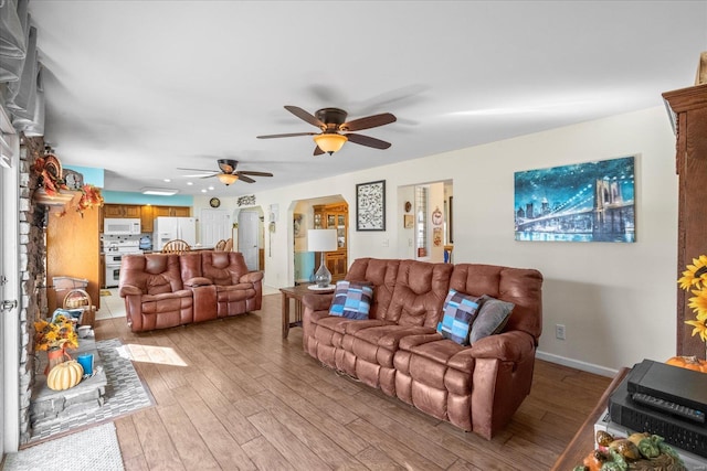 living room with ceiling fan, light wood finished floors, and baseboards