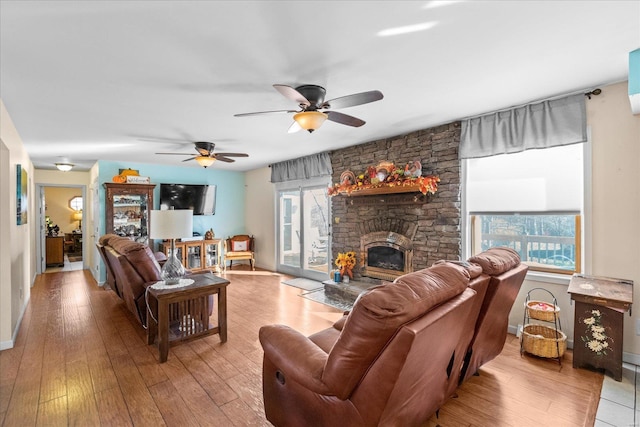 living room with a stone fireplace, hardwood / wood-style flooring, and baseboards