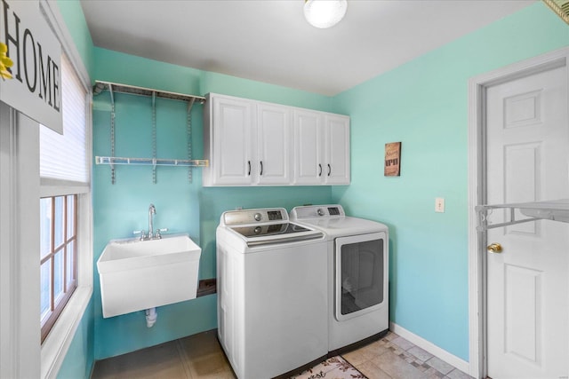 laundry room with cabinet space, washing machine and dryer, baseboards, and a sink