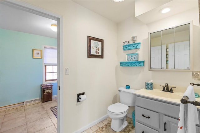 bathroom with toilet, visible vents, vanity, baseboards, and tile patterned floors