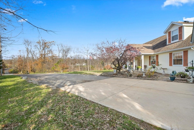 view of yard with concrete driveway and a porch