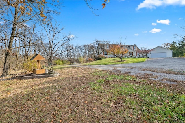 view of yard with a garage, aphalt driveway, and an outdoor structure