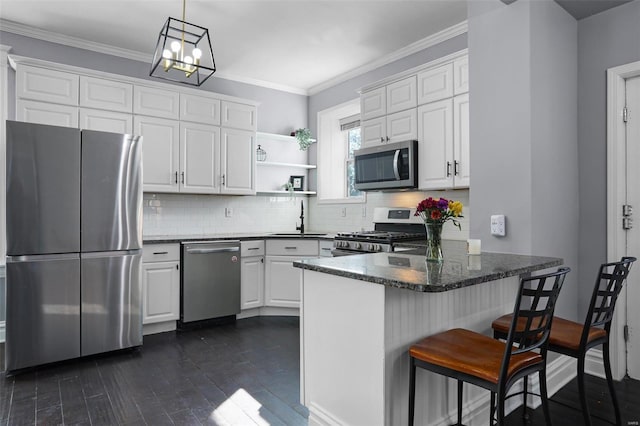 kitchen featuring a peninsula, white cabinetry, stainless steel appliances, and a sink