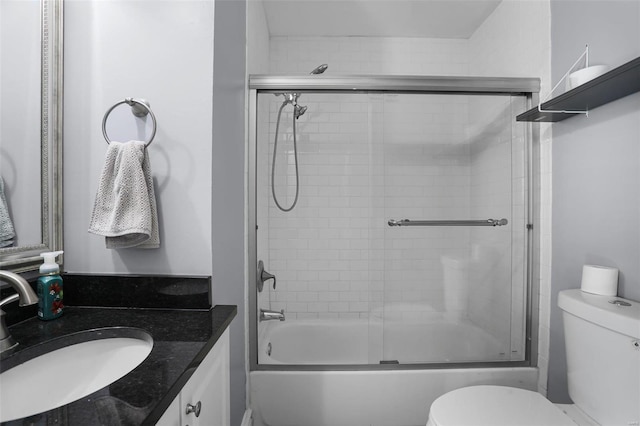 bathroom featuring toilet, combined bath / shower with glass door, and vanity