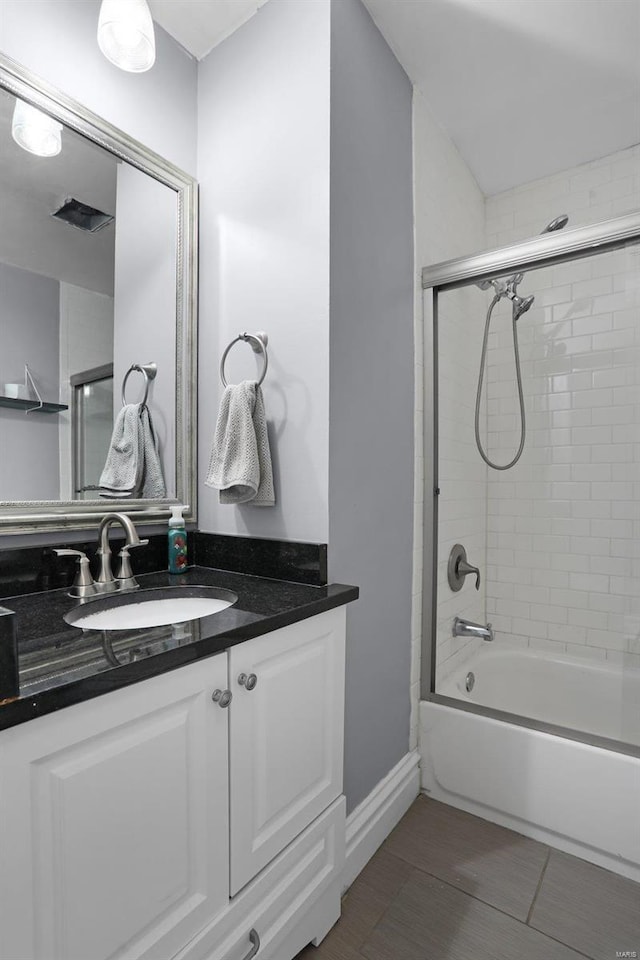 full bath with bath / shower combo with glass door, vanity, and baseboards