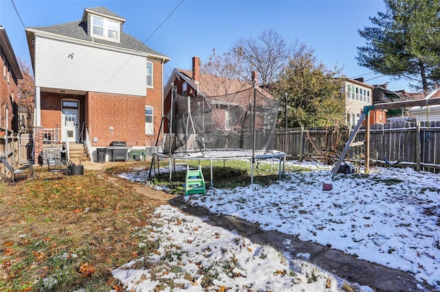 yard covered in snow with a trampoline and fence