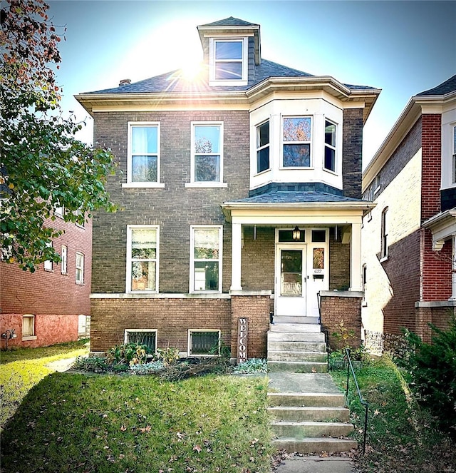 american foursquare style home featuring brick siding and a front yard