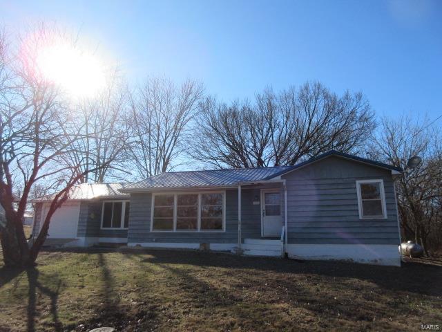 view of front facade with a garage, a front yard, and metal roof