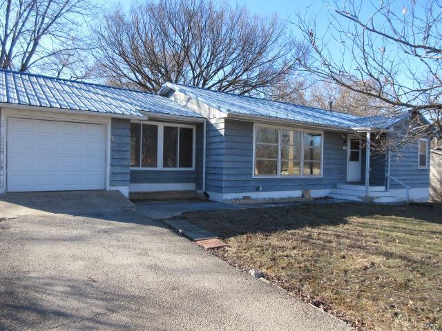 ranch-style house with a garage, metal roof, and driveway