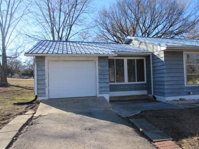 view of front of home with driveway, a garage, and metal roof