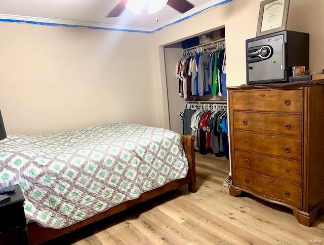 bedroom with a closet, crown molding, light wood-style flooring, and ceiling fan