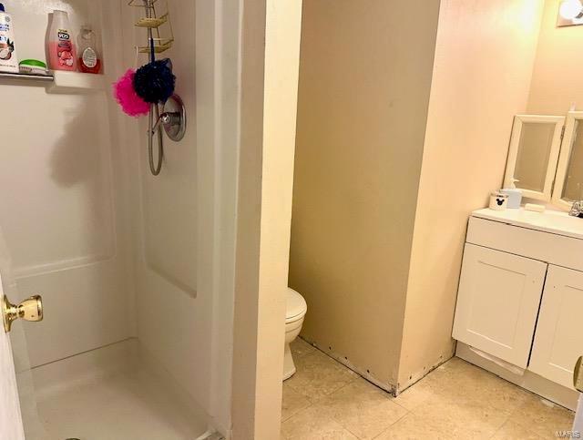 bathroom with toilet, a stall shower, and vanity