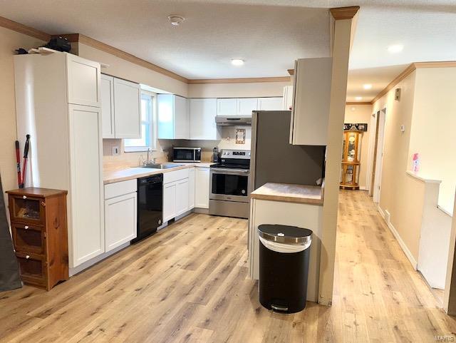 kitchen with light wood-style flooring, under cabinet range hood, stainless steel appliances, a sink, and crown molding