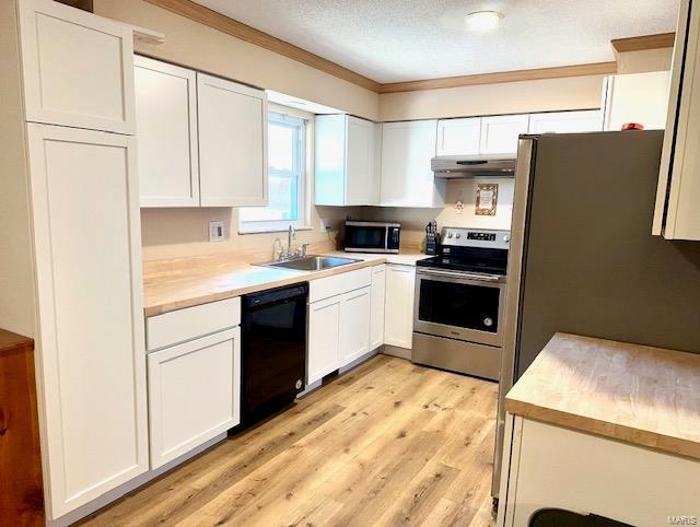 kitchen featuring light countertops, appliances with stainless steel finishes, white cabinets, a sink, and under cabinet range hood