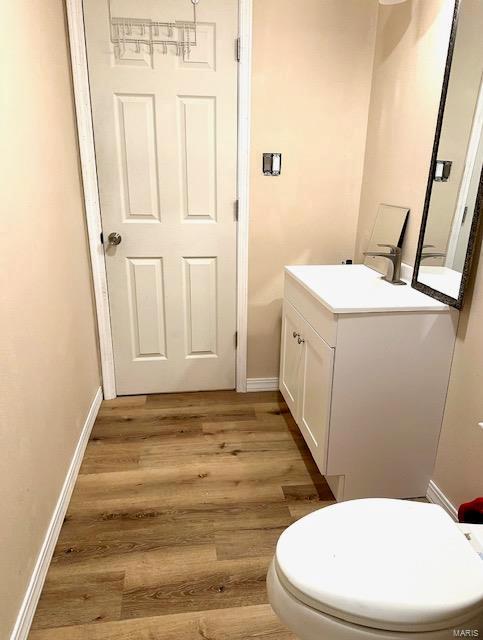 bathroom featuring toilet, wood finished floors, vanity, and baseboards