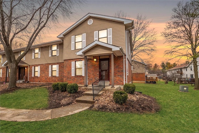 view of front of property with a yard and brick siding