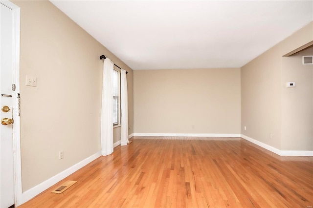 unfurnished room with visible vents, light wood-style flooring, and baseboards