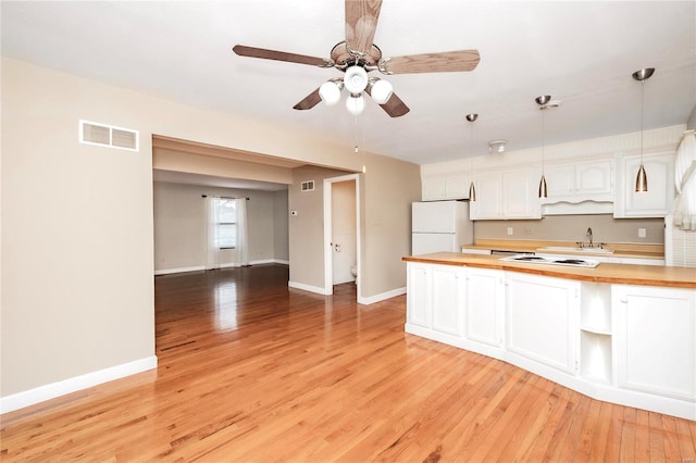 kitchen with white appliances, visible vents, butcher block counters, light wood-type flooring, and white cabinetry