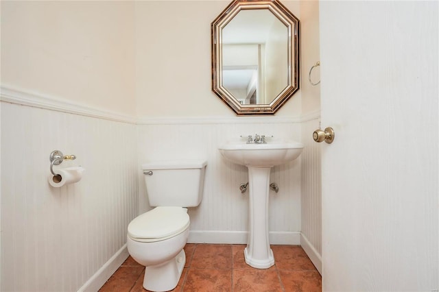 half bath featuring toilet, baseboards, a sink, and tile patterned floors