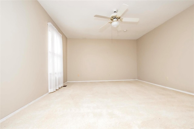 empty room with baseboards, ceiling fan, and light colored carpet