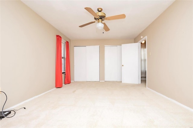 unfurnished bedroom featuring a ceiling fan, carpet, baseboards, and two closets