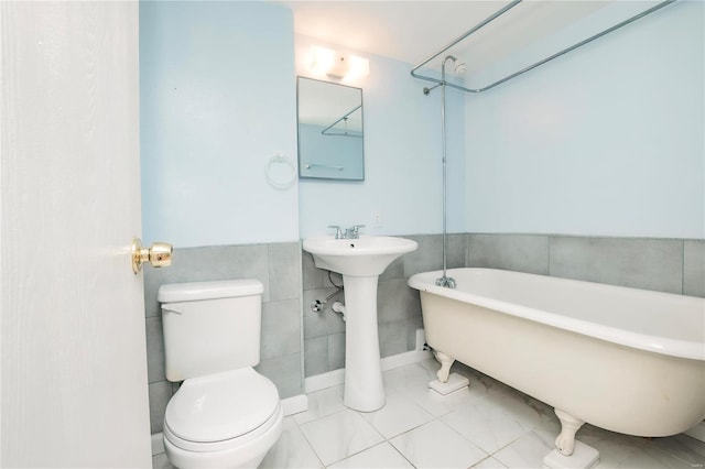 full bathroom featuring toilet, a soaking tub, and tile walls