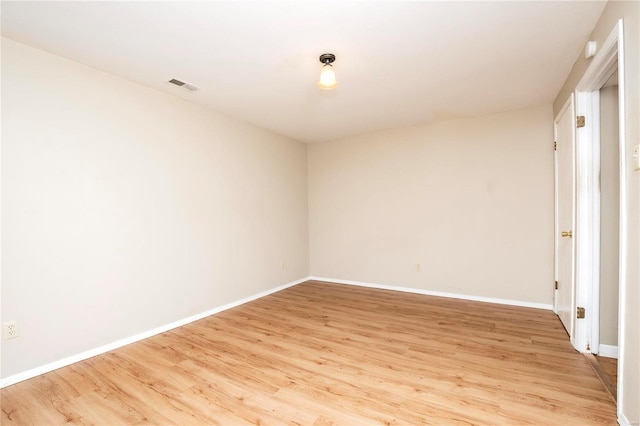 spare room with baseboards, visible vents, and light wood finished floors