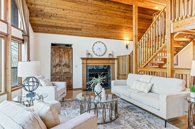 living room featuring a premium fireplace, wooden ceiling, wood finished floors, and stairway