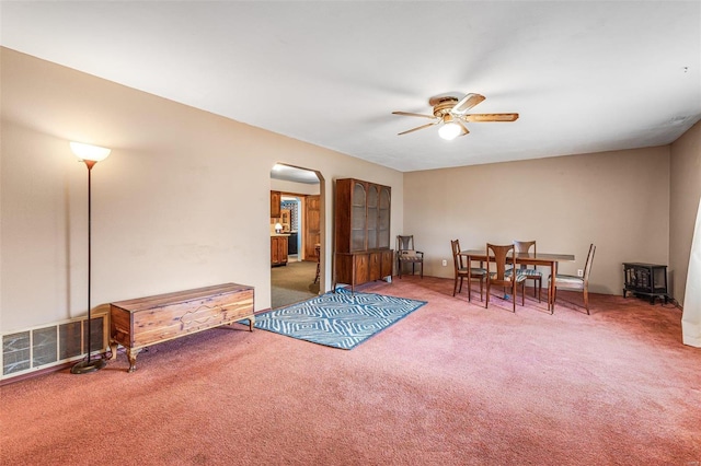 interior space featuring arched walkways, carpet, visible vents, and a ceiling fan