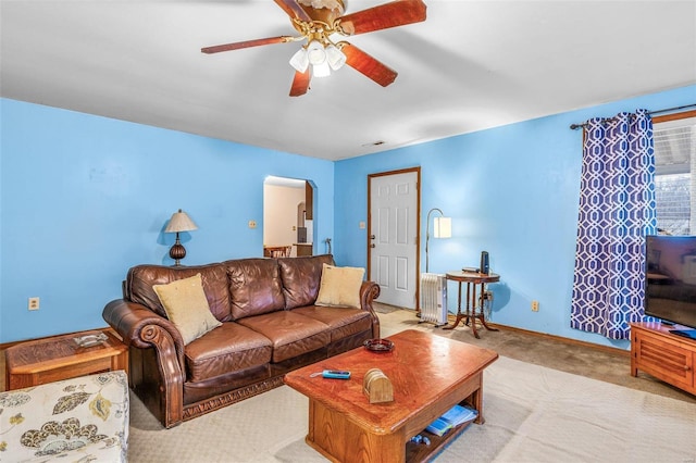 living area with carpet floors, arched walkways, visible vents, a ceiling fan, and baseboards