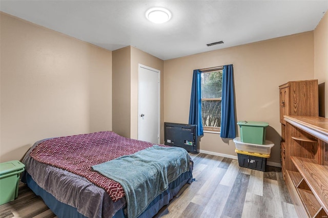 bedroom featuring visible vents, baseboards, and wood finished floors