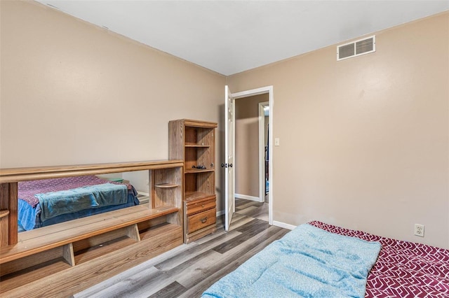 bedroom with wood finished floors, visible vents, and baseboards